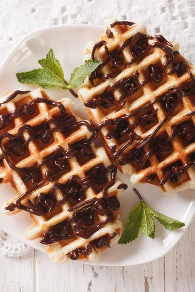 Dessert waffles with chocolate topping on a plate close-up. vert