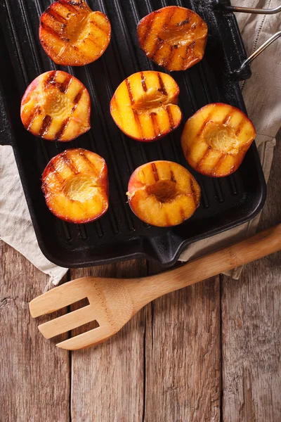Summer dessert: Cooking Ripe peaches on a grill pan close-up. Ve