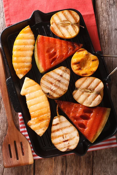 Apples, melon, pear, watermelon and peach on a grill pan close-u