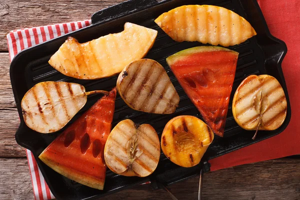 Grilled apple, melon, pear, watermelon and peach on a grill. Hor