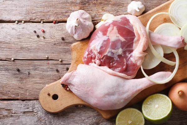 Fresh raw duck legs on a cutting board with lime, top view