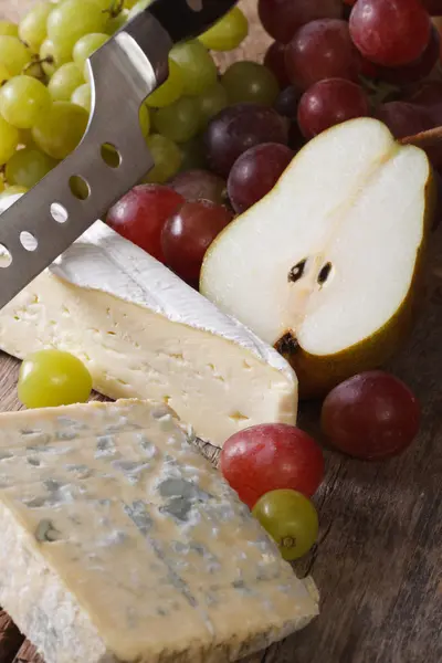 Molded cheese, grapes and pears close-up vertical