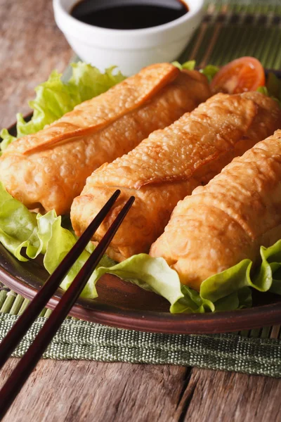 Fried spring rolls on a plate and chopsticks close-up. vertical
