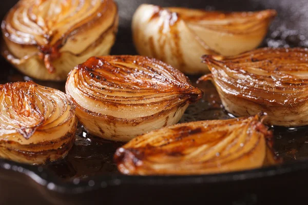 Caramelized onion halves with balsamic vinegar in a pan