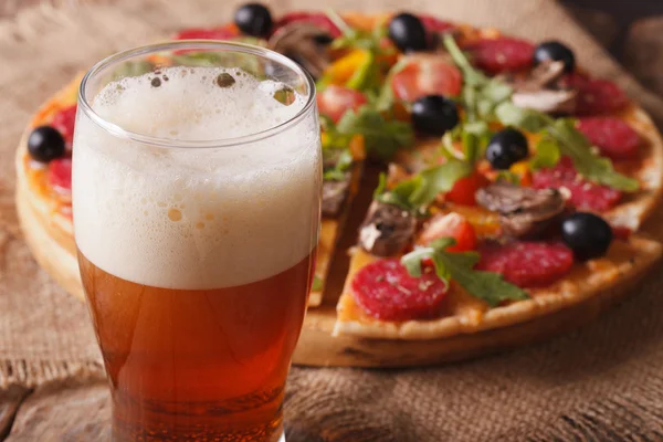 Beer with foam close-up on background pizza