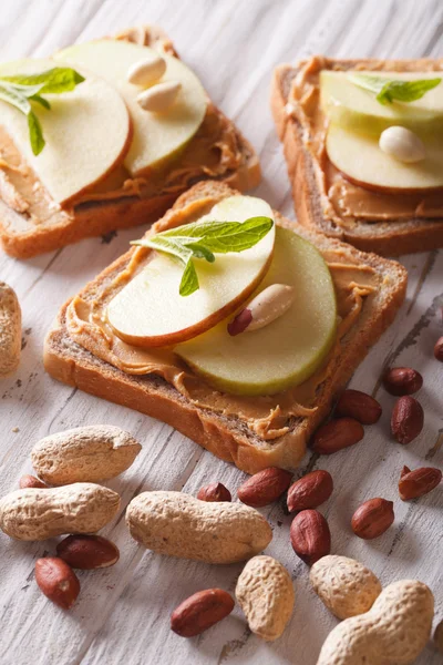 Toast with fresh apple and peanut butter on the table. vertical