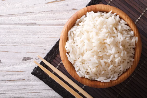 Steamed rice in a wooden bowl and chopsticks. horizontal top vie