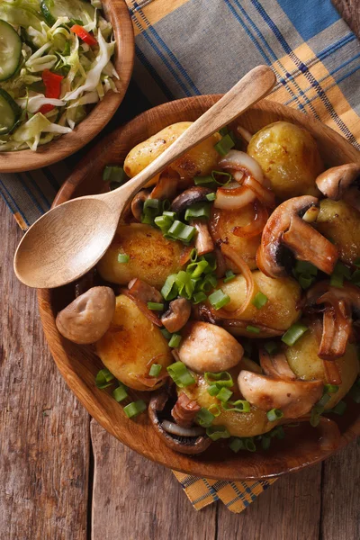 Potatoes with mushrooms and fresh salad in a rustic, top view