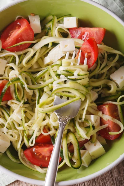 Zucchini pasta with feta and tomatoes macro. vertical top view