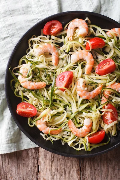 Zucchini pasta with shrimp and tomato close-up. Vertical top vie