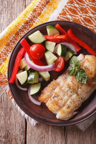 Grilled white fish with vegetables close-up. vertical top view