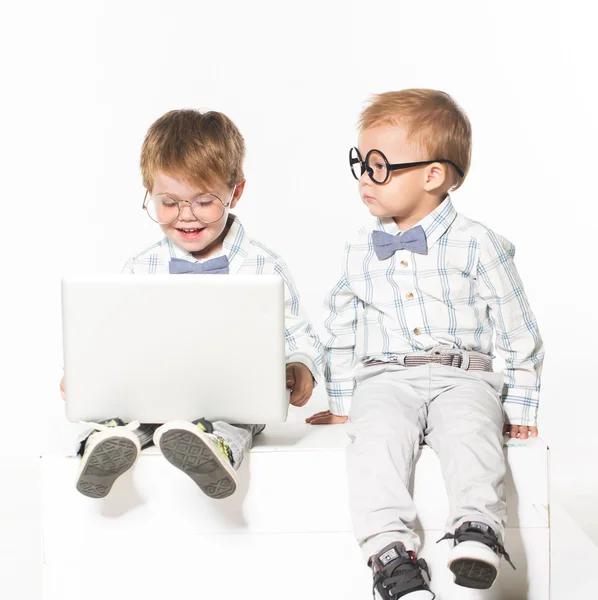 Two cute baby with laptop isolated in studio.