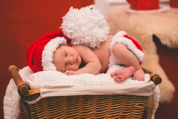Portrait of sleeping newborn baby boy in Santa clothes.