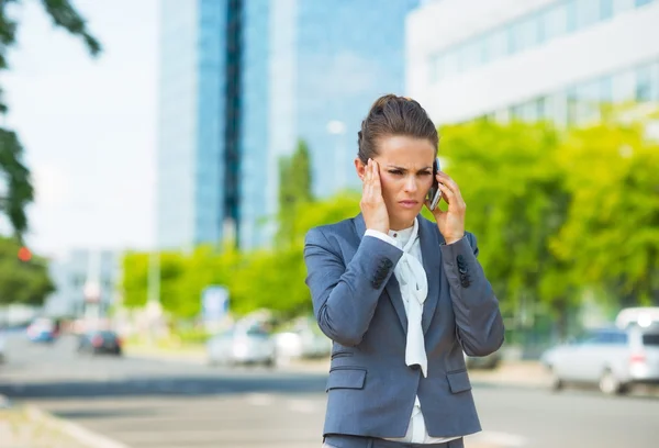 Stressed business woman in office district talking smartphone