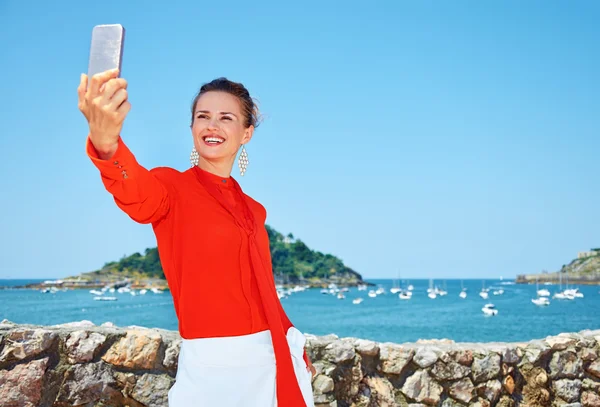 Happy woman taking selfie in front of lagoon with yachts