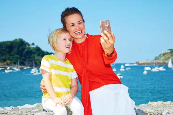Mother and daughter taking selfie in front of lagoon