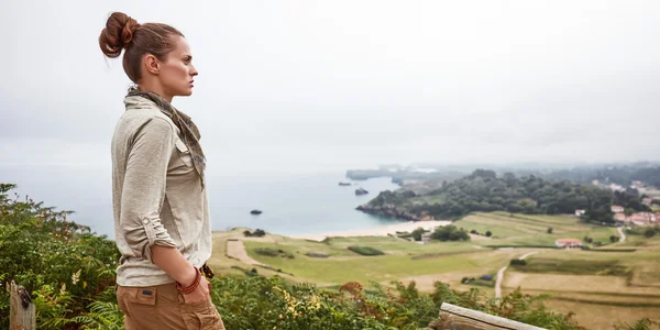 Woman looking into distance in front of ocean view landscape