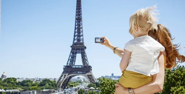 Mother and child taking photo with camera against Eiffel tower