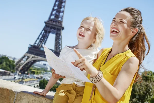 Mother and child tourists holding map and pointing. Paris