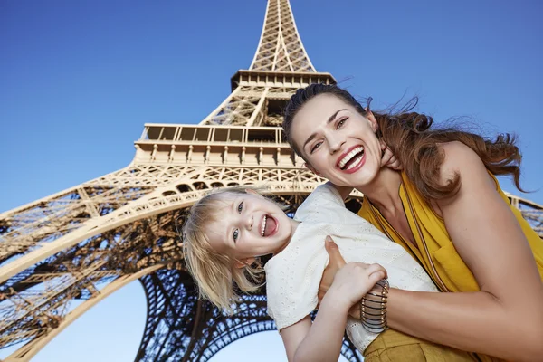 Cheerful mother and daughter travellers against Eiffel tower