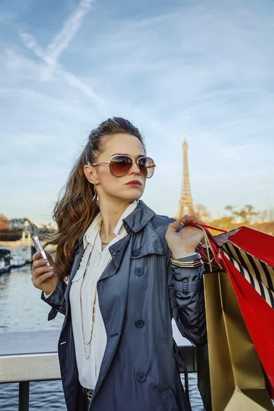 Trendy woman with shopping bags in Paris looking into distance