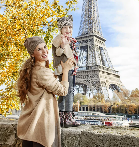Mother and child travelers handwaving on embankment in Paris