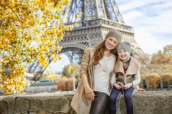 Mother and child tourists sitting on the parapet in Paris