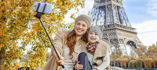 Mother and child tourists taking selfie on embankment In Paris