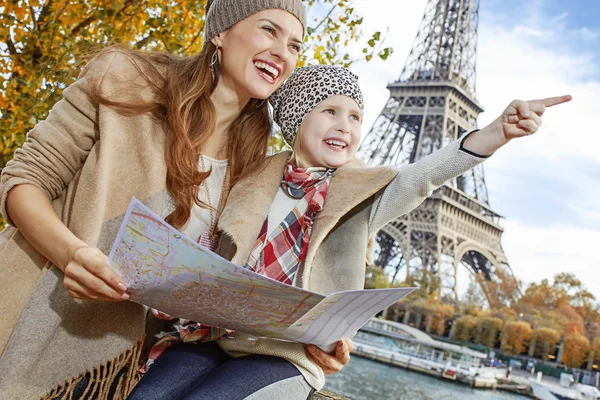Mother and daughter tourists in Paris holding map and pointing