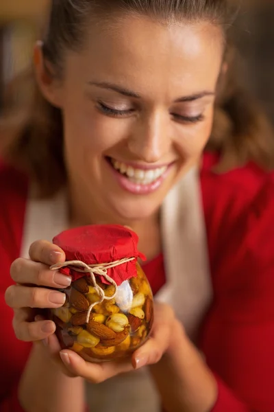 Portrait of happy young housewife holding jar with honey nuts