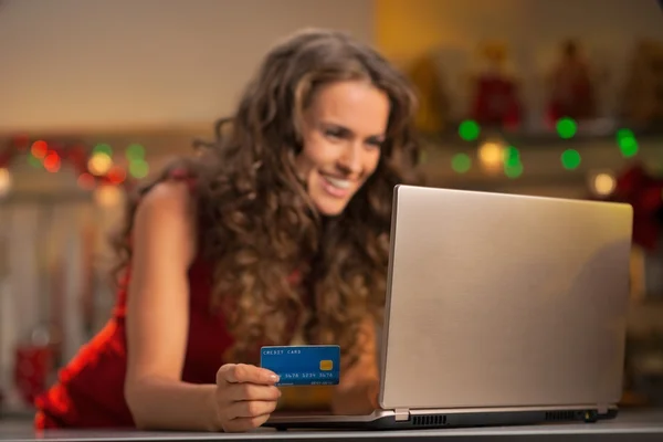 Closeup on happy young woman with credit card using laptop