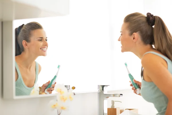 Young woman looking in mirror after brushing teeth