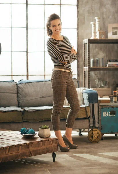 Full length portrait of happy young woman standing in loft apart