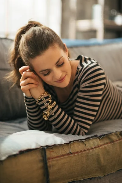 Relaxed young woman laying on divan in loft apartment