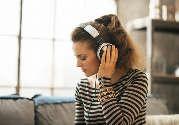 Portrait of young woman listening music in headphones in loft ap