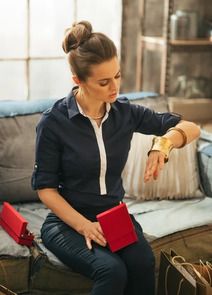 Young woman with shopping bags trying jewelry in loft apartment