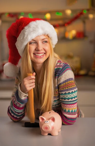 Portrait of smiling teenager girl in santa hat with piggy bank a