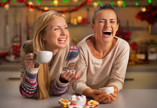 Portrait of laughing girlfriends having christmas snacks in chri