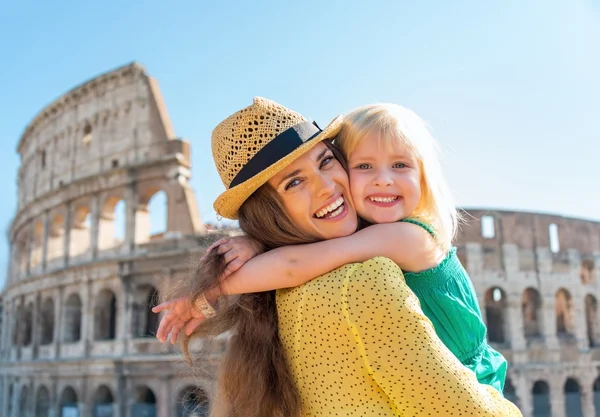 Portrait of mother and baby girl hugging in front of colosseum i