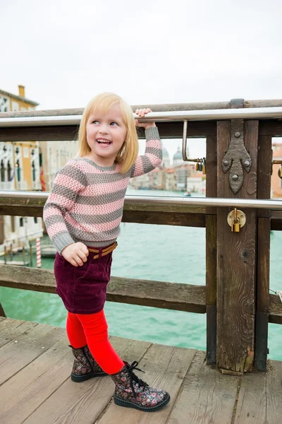 Happy blonde girl looking over shoulder on bridge in Venice