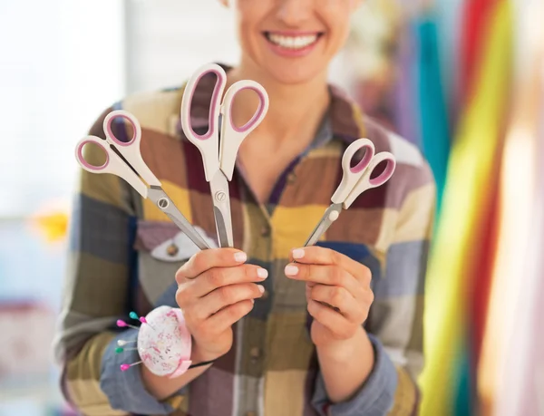 Closeup on happy tailor woman showing scissors