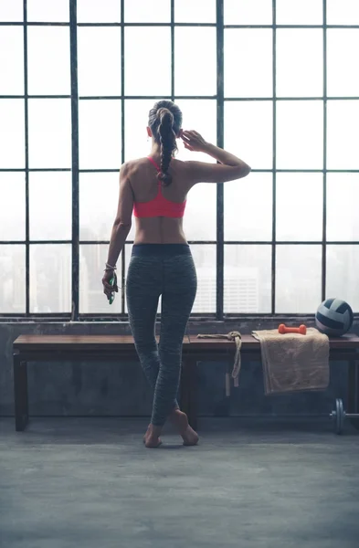 Rear view of fit woman in loft gym listening to music