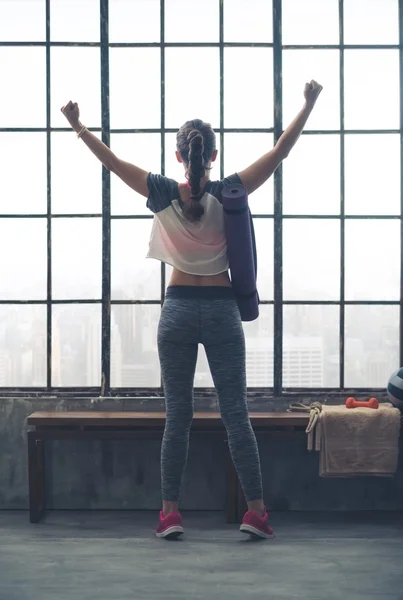 Rear view of woman rejoicing in city loft gym