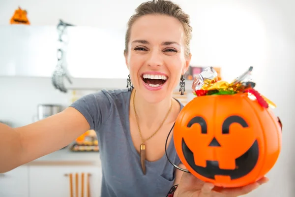 Happy woman making selfie with halloween bucket full of candy