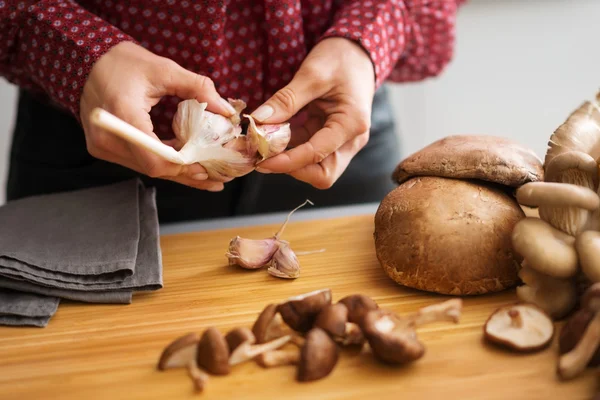 Woman\'s hands separating cloves of garlic with mushrooms