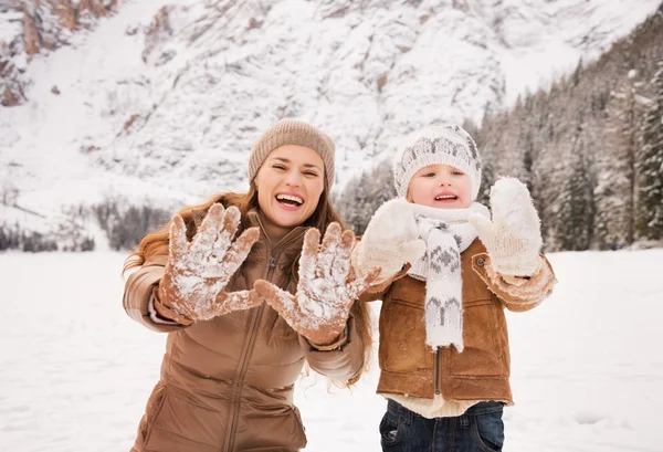 Mother and child showing snowy gloves in winter outdoors