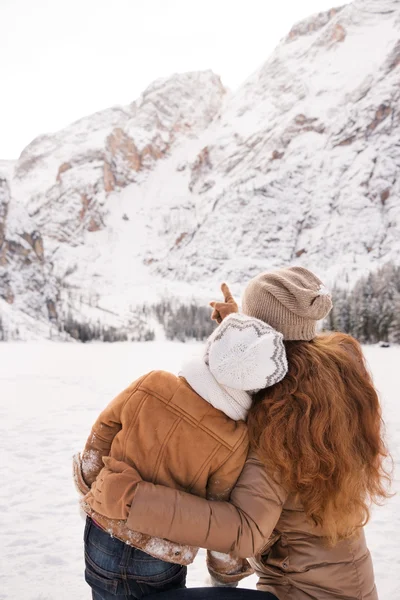 Seen from behind mother pointing child on snow-capped mountains