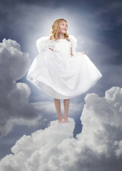 Child angel standing on fluffy clouds in the sky