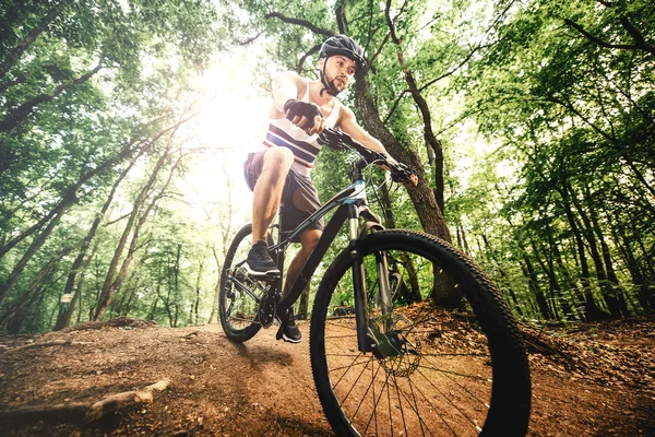 Cyclist with helmet riding mountain bike on rocky forest trail a