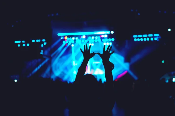 Silhouette of a woman making hand gestures, vintage look on photo, stage and crowd background